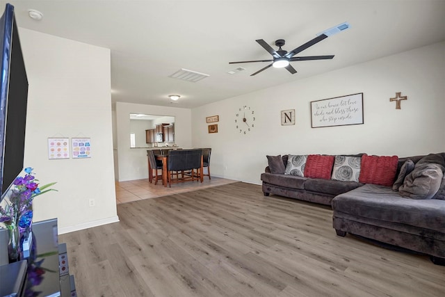 living room with baseboards, wood finished floors, visible vents, and ceiling fan