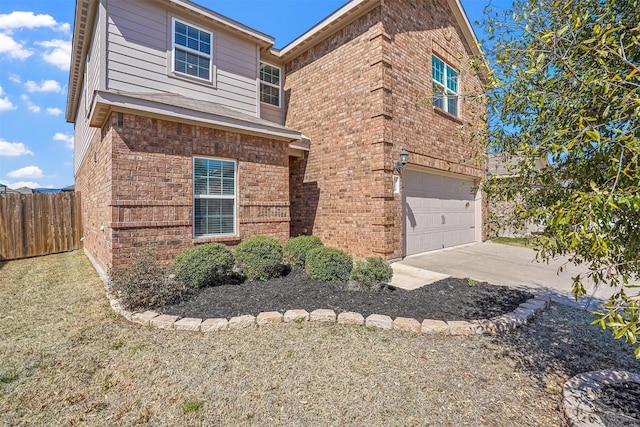 traditional home with brick siding, driveway, an attached garage, and fence