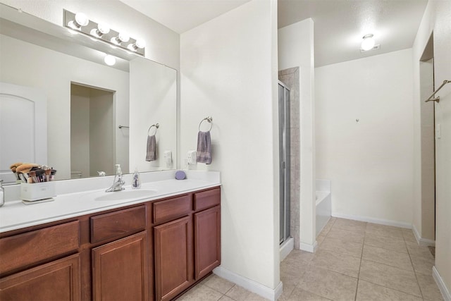 bathroom with baseboards, vanity, a shower stall, and tile patterned flooring