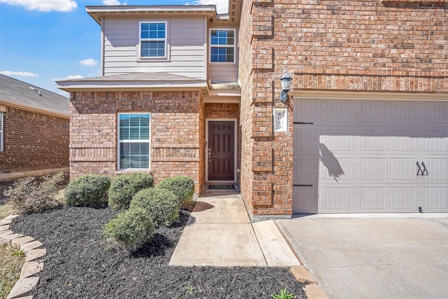 view of exterior entry with brick siding and driveway