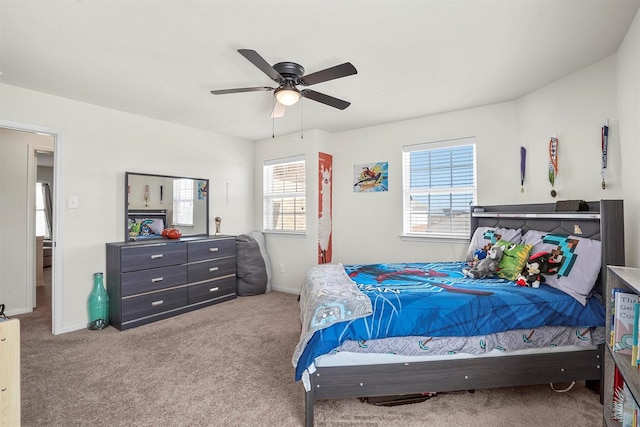 carpeted bedroom featuring baseboards, multiple windows, and a ceiling fan