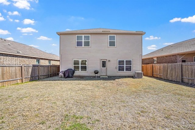 back of property with a fenced backyard, central AC unit, and a yard