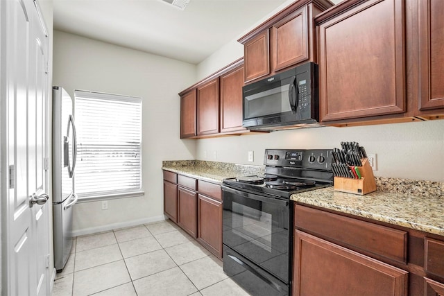 kitchen with light tile patterned flooring, baseboards, black appliances, and light stone counters