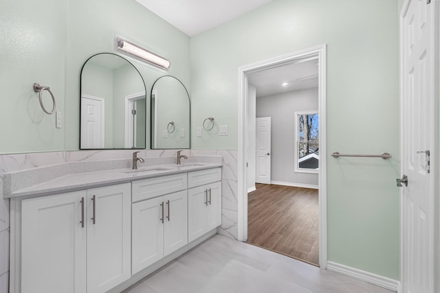 bathroom featuring double vanity, baseboards, and a sink