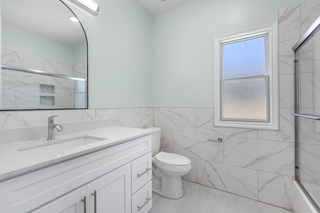 full bathroom featuring a marble finish shower, toilet, vanity, and tile walls