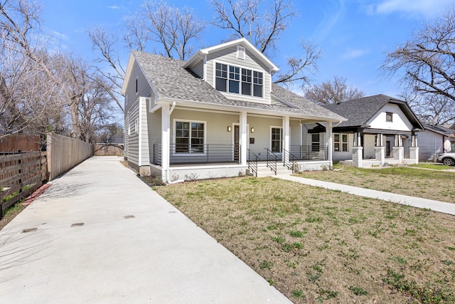 bungalow-style house with fence, driveway, roof with shingles, covered porch, and a front lawn