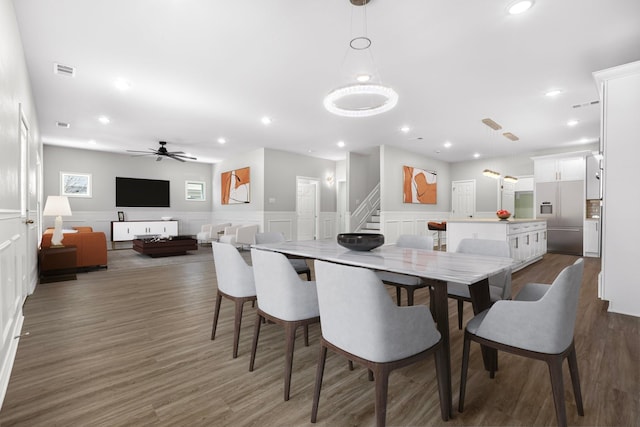 dining area featuring a ceiling fan, dark wood-style flooring, visible vents, and a wainscoted wall