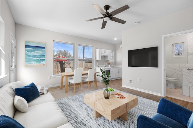 living area featuring recessed lighting, ceiling fan, baseboards, and light wood-style floors