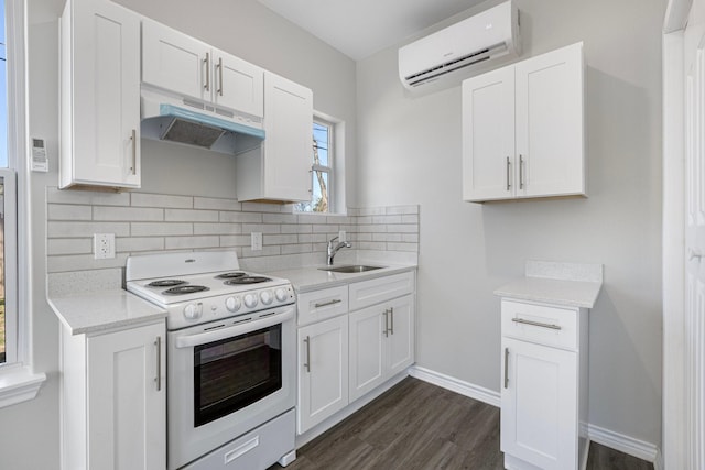 kitchen with electric range, a wall mounted AC, under cabinet range hood, a sink, and light countertops