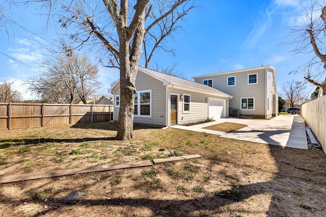 rear view of house featuring a garage, a fenced backyard, and driveway