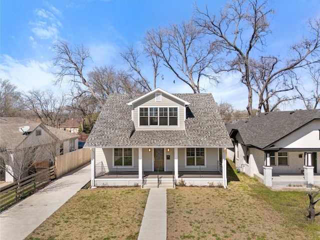 bungalow featuring a porch, driveway, a front lawn, and fence