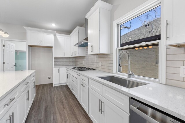 kitchen featuring a sink, backsplash, appliances with stainless steel finishes, white cabinets, and dark wood-style flooring