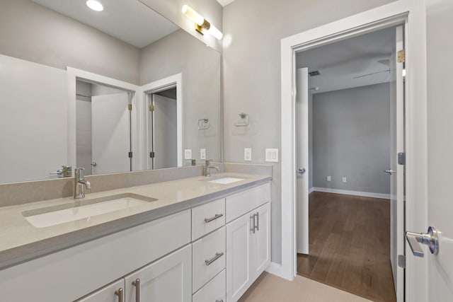 bathroom featuring double vanity, wood finished floors, baseboards, and a sink