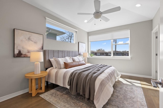 bedroom with multiple windows, wood finished floors, and baseboards