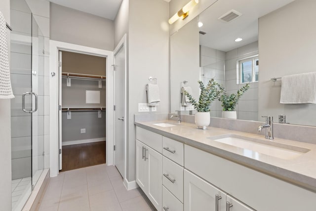 full bathroom with a spacious closet, visible vents, a stall shower, and a sink