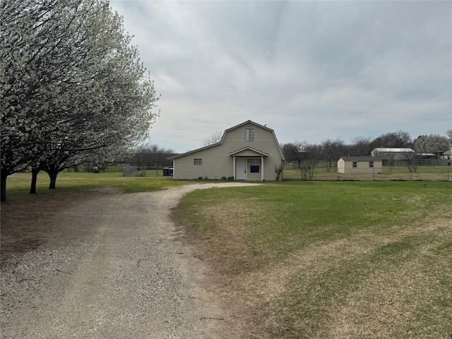 view of front of house featuring a gambrel roof, driveway, a front yard, and fence