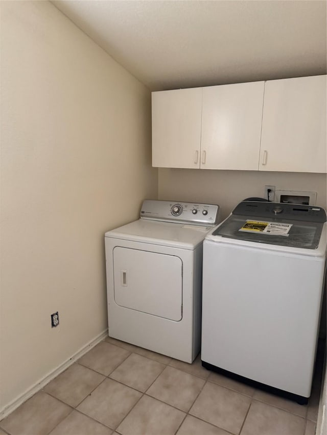 clothes washing area featuring light tile patterned floors, cabinet space, independent washer and dryer, and baseboards