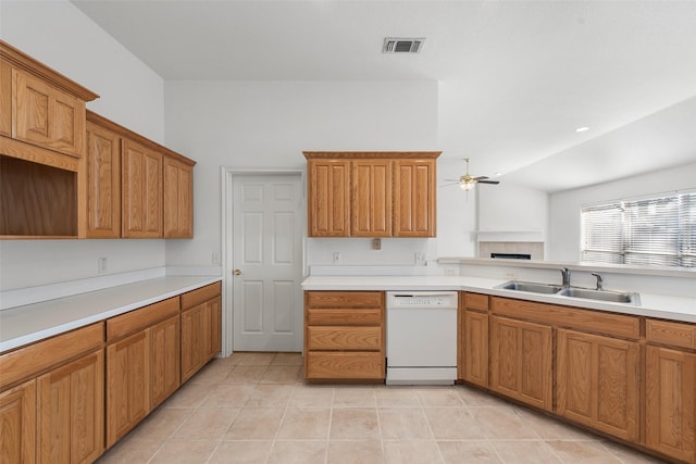 kitchen featuring brown cabinets, a ceiling fan, a sink, a fireplace, and dishwasher