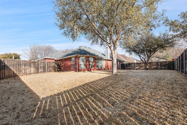 rear view of property with brick siding and a fenced backyard