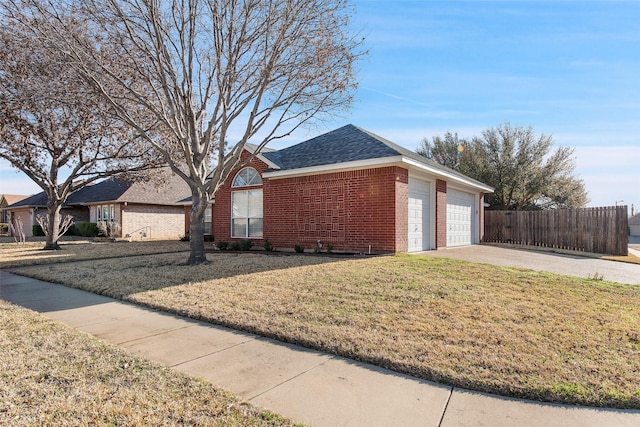 view of side of property with brick siding, a shingled roof, fence, a lawn, and driveway