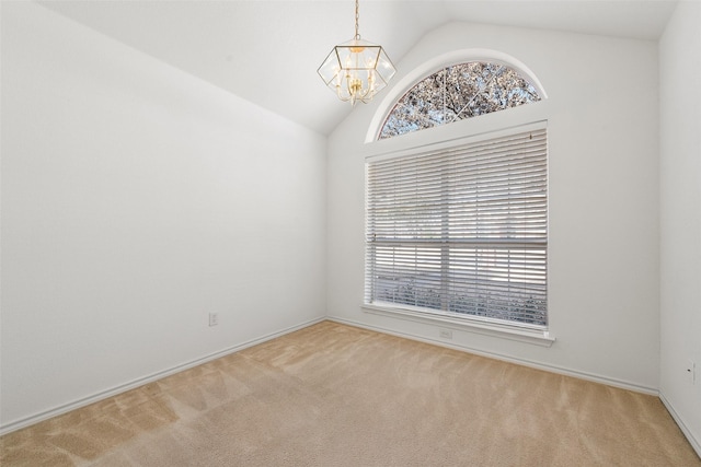 carpeted spare room with an inviting chandelier and vaulted ceiling