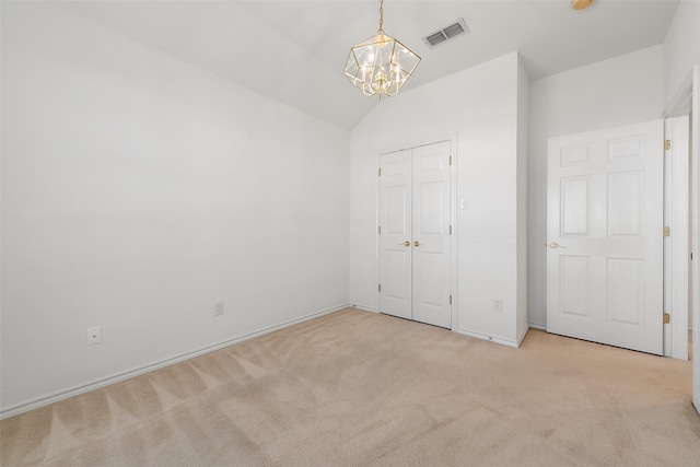 unfurnished bedroom with visible vents, lofted ceiling, carpet flooring, a closet, and a notable chandelier