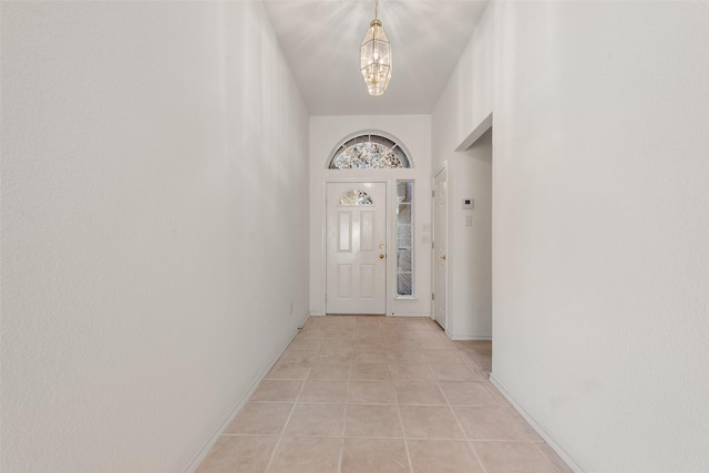 entryway featuring baseboards, an inviting chandelier, and light tile patterned flooring