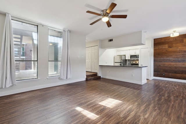 unfurnished living room featuring visible vents, baseboards, dark wood-style flooring, and a ceiling fan