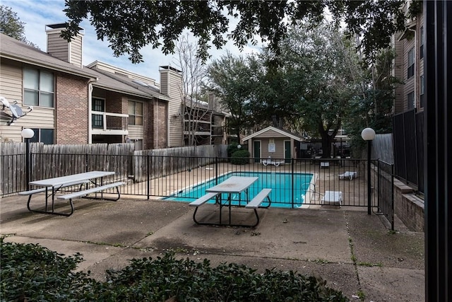 pool featuring a diving board, a patio, and fence