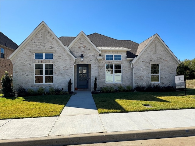 french provincial home with brick siding and a front lawn