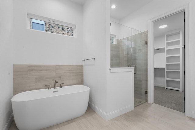 bathroom with a freestanding tub, a walk in closet, and a shower stall