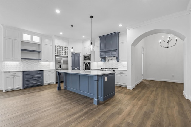 kitchen with open shelves, white cabinetry, arched walkways, light countertops, and built in appliances