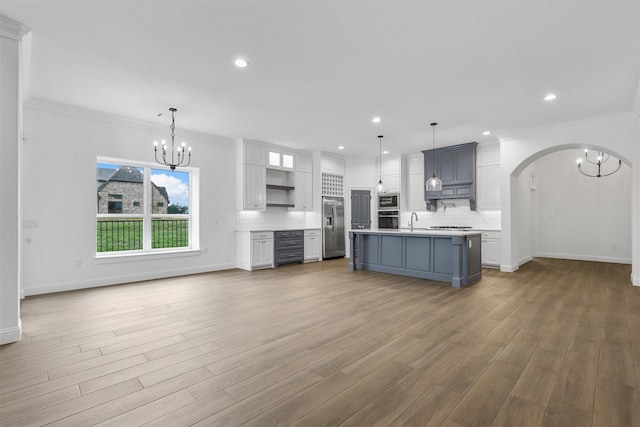 kitchen featuring backsplash, stainless steel appliances, white cabinets, light countertops, and a chandelier