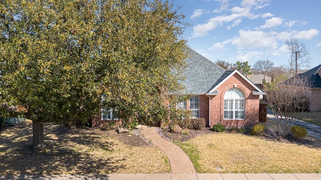 view of front of house featuring brick siding and roof with shingles