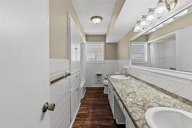 6305 Chapman Dr, Greenville, TX 75402 - bathroom with tile walls, double vanity, toilet, a textured ceiling, and a wainscoted wall