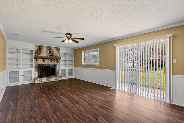 6305 Chapman Dr, Greenville, TX 75402 - unfurnished living room featuring a textured ceiling, a ceiling fan, wood finished floors, a fireplace, and built in shelves