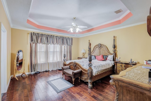 bedroom featuring a raised ceiling, crown molding, visible vents, and dark wood-style flooring