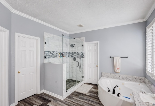 bathroom with a tub with jets, a stall shower, a textured ceiling, and wood finished floors