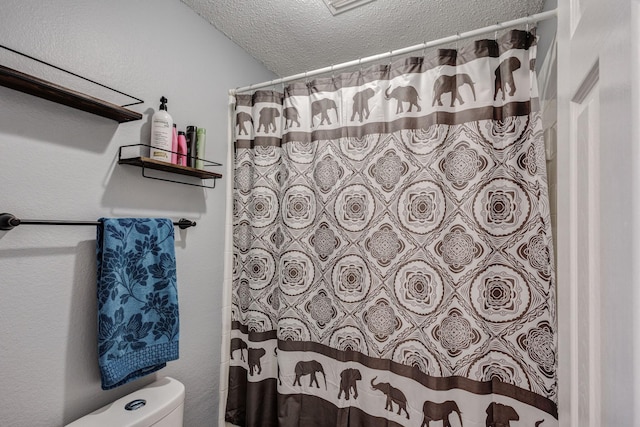 full bathroom featuring a shower with shower curtain, a textured ceiling, and toilet