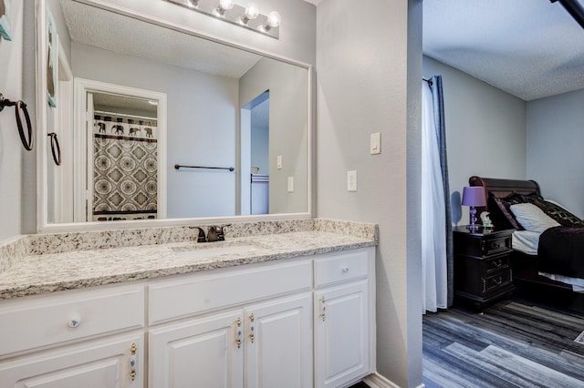 full bathroom with a textured ceiling, vanity, and wood finished floors