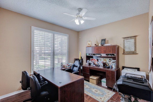 home office featuring dark wood-type flooring, a ceiling fan, baseboards, and a textured ceiling