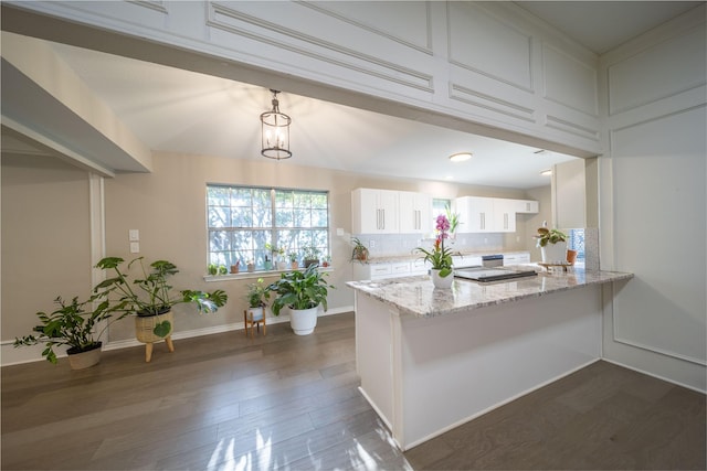 kitchen featuring tasteful backsplash, dark wood-type flooring, light stone counters, a peninsula, and white cabinetry