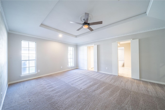 unfurnished bedroom with baseboards, carpet, ornamental molding, ensuite bathroom, and a raised ceiling