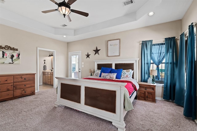 bedroom featuring a tray ceiling, visible vents, and carpet floors