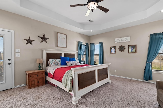 bedroom featuring visible vents, baseboards, a tray ceiling, carpet flooring, and a ceiling fan