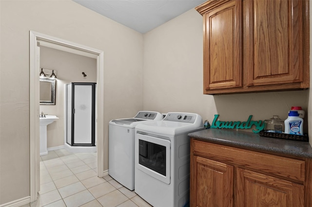 laundry area with light tile patterned flooring, cabinet space, baseboards, and washing machine and clothes dryer