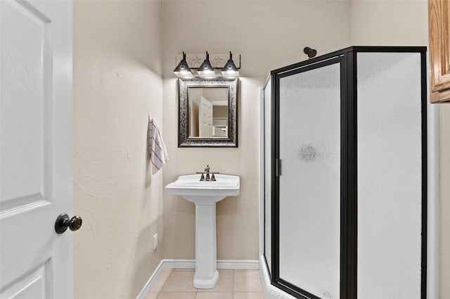 bathroom featuring tile patterned floors, baseboards, a stall shower, and a sink