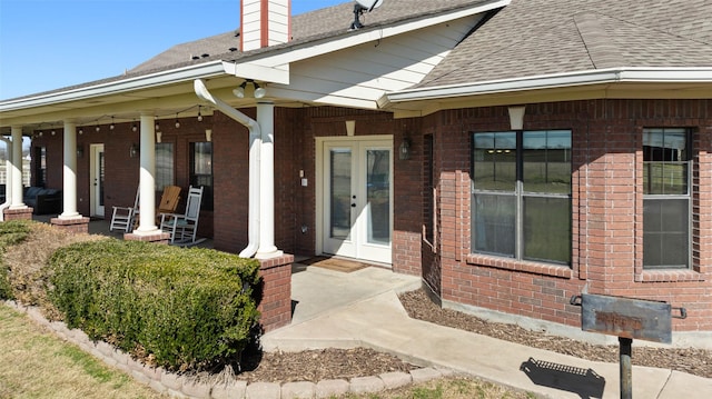 view of exterior entry featuring brick siding, french doors, and a chimney