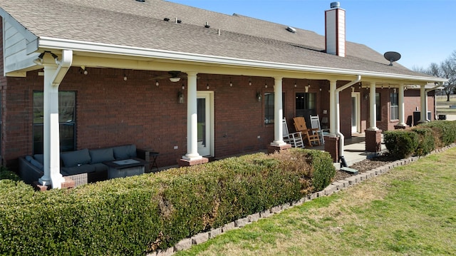 rear view of house featuring brick siding, an outdoor living space, and a patio