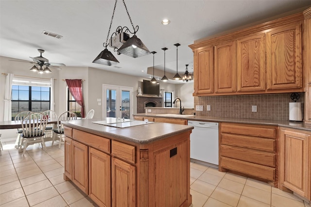 kitchen with visible vents, a kitchen island, white dishwasher, a sink, and electric cooktop